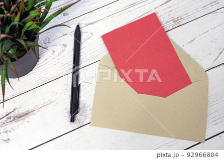 Red card mockup with envelope, pen and potted plant on wooden table. 92966804