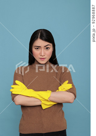 Asian tired angry and frustrated asian housekeeper at work wearing yellow glove against a blue background, Housewife worker, Cleaning home concept, Unhappy stressed and overworked woman Asian tired angry and frustrated asian housekeeper at work wearing yellow glove against a blue background, Housewife worker, Cleaning home concept, Unhappy stressed and overworked woman 92968887