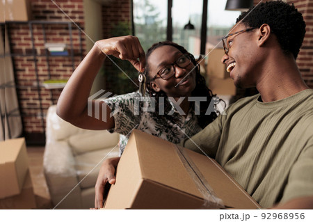 African american couple feeling happy about new property, holding keys to family house and moving in together. Homeowners celebrating life achievement and starting new beginnings. 92968956