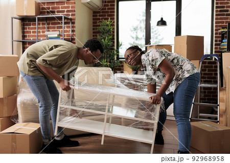African american couple moving in new apartment together, unpacking furniture to decorate household. Enjoying relocation after buying first house to start new beginnings and celebrate life event. African american couple moving in new apartment together, unpacking furniture to decorate household. Enjoying relocation after buying first house to start new beginnings and celebrate life event. 92968958