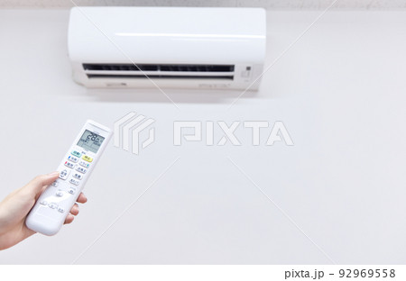 エアコン　冷房時の室温28度　リモコンを操作する女性の手 92969558