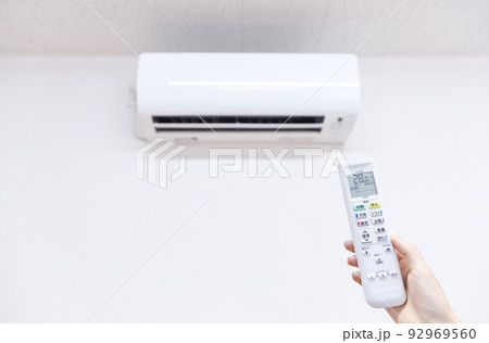 エアコン　冷房時の室温28度　リモコンを操作する女性の手 92969560
