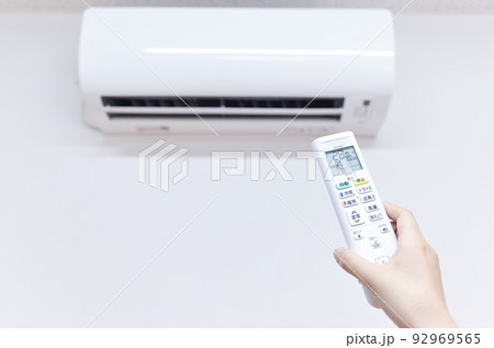 エアコン　冷房時の室温28度　リモコンを操作する女性の手 92969565