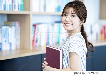 本を持つ眼鏡の若い女性 本を持つ眼鏡の若い女性 92970035