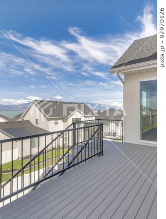 Vertical Whispy white clouds Deck of a house with stairs, wood flooring, and metal railings 92970126