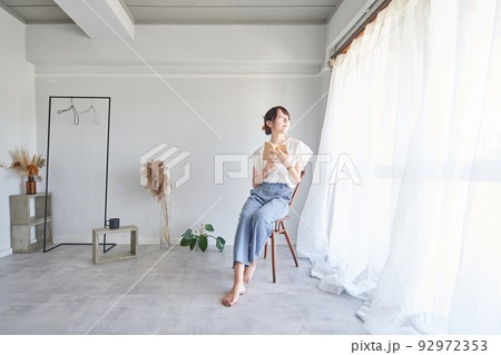 シンプルな部屋で本を読む女性 92972353