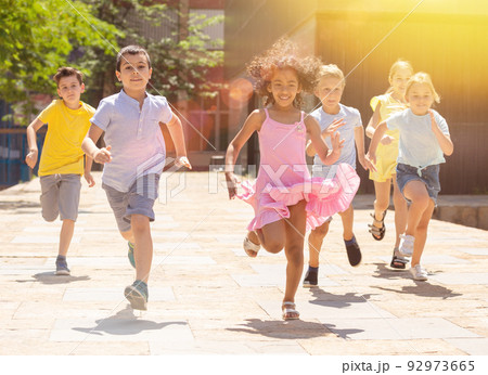 Team of positive kids running in race in the street and laughing Team of positive kids running in race in the street and laughing 92973665
