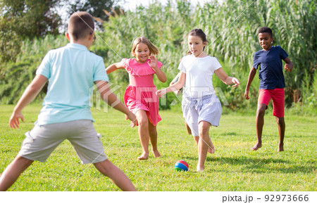 Boys and girls playing football outdoors Boys and girls playing football outdoors 92973666