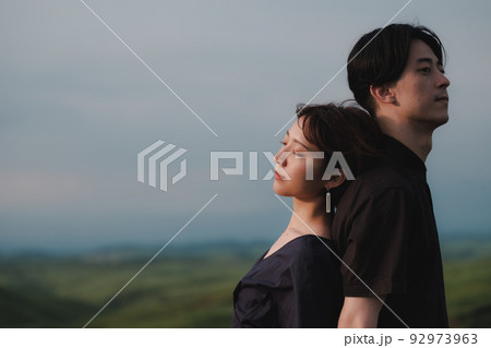 自然の中で背中合わせの男女 92973963
