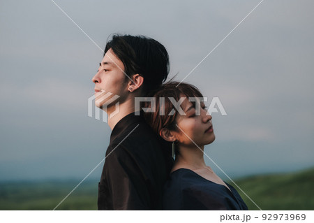自然の中で背中合わせの男女 92973969