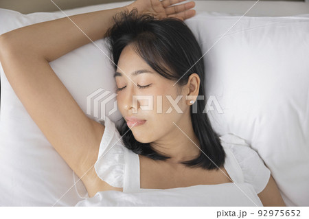 Young Asian woman sleeping in her bed and relaxing in bedroom. they are lying on the side and relax with their eyes closed Young Asian woman sleeping in her bed and relaxing in bedroom. they are lying on the side and relax with their eyes closed 92975652