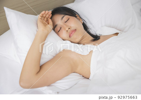Young asian woman sleeping in bed at bedroom. she is lying on side and relax with eyes closed Young asian woman sleeping in bed at bedroom. she is lying on side and relax with eyes closed 92975663
