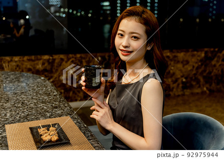 焼き鳥と日本酒を楽しむ女性 92975944