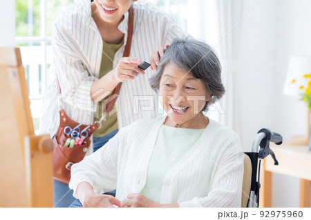 美容師さんに髪のお手入れをしてもらうシニア女性 92975960