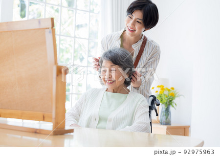 美容師さんに髪のお手入れをしてもらうシニア女性 92975963