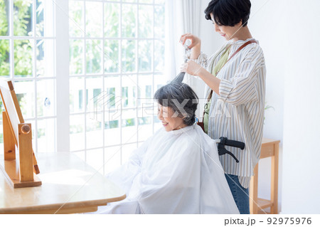 美容師さんに髪のお手入れをしてもらうシニア女性 92975976
