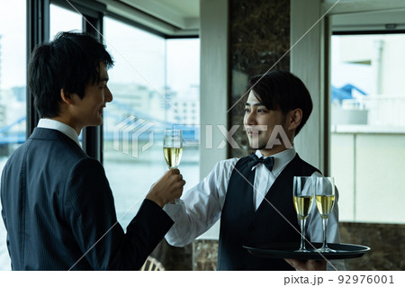 シャンパンを渡すウエイター 92976001