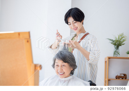 美容師さんに髪のお手入れをしてもらうシニア女性 92976066
