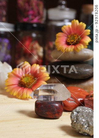Quartz Crystal Balanced on Bloodstone With Flowers in Background Shallow DOF Quartz Crystal Balanced on Bloodstone With Flowers in Background Shallow DOF 92978206