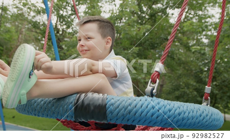 4K. A boy rides on a swing in the park in summer 92982527