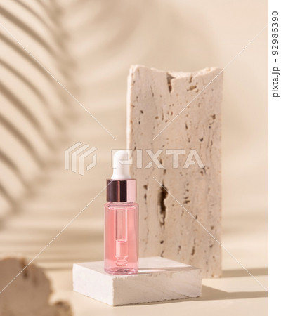 Dropper Bottle on travertine stone and palm leaf shadow on light yellow Dropper Bottle on travertine stone and palm leaf shadow on light yellow 92986390