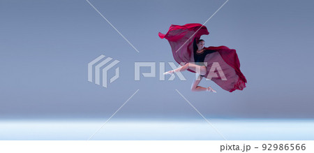 Portrait of young ballerina dancing with deep red fabric isolated over blue grey studio background. Flying like a butterfly Portrait of young ballerina dancing with deep red fabric isolated over blue grey studio background. Flying like a butterfly 92986566