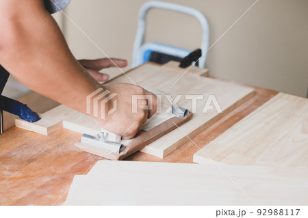 Woodworking entrepreneurs are using sandpaper to decorate wooden pieces to assemble and build wooden tables for their clients 92988117