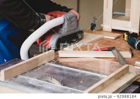Woodworking entrepreneurs use sandpaper finishing machines to assemble and build wooden tables for their clients. 92988184