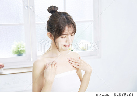 リビングで胸元のケアをする女性 92989532
