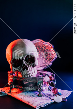 Human skull and treasure in copper vintage box on the map in neon red and blue light on dark background. Pirate treasure, treasure seekers concept . Vertical card. Selective focus, copy space 92991633