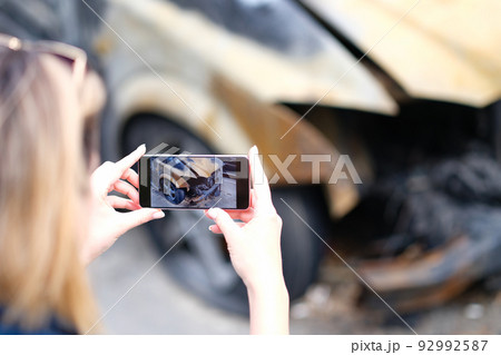 Closeup of female insurance broker taking photos of car after fire accident Closeup of female insurance broker taking photos of car after fire accident 92992587