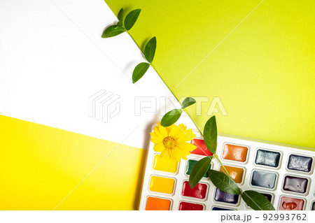 Watercolor paints in a box on a white, yellow and green background 92993762