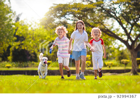 Kids play with dog. Children and puppy run in park Kids play with dog. Children and puppy run in park 92994367