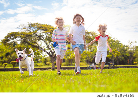 Kids play with dog. Children and puppy run in park Kids play with dog. Children and puppy run in park 92994369