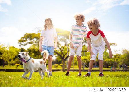 Kids play with dog. Children and puppy run in park Kids play with dog. Children and puppy run in park 92994370