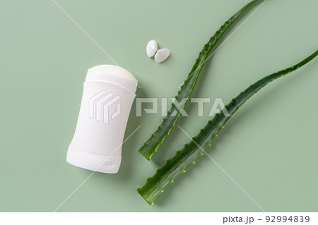 Solid antiperspirant deodorant and sea shell butterfly near fresh aloe leaves over green background. Solid antiperspirant deodorant and sea shell butterfly near fresh aloe leaves over green background. 92994839