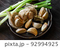Garlic cloves with scallion on dark ceramic plate. 92994925