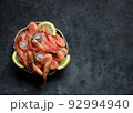 Raw shrimps with lemon and ice on a dark background. 92994940