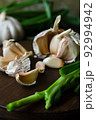 Garlic cloves in composition with scallion on a dark background. 92994942