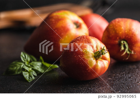Bull heart tomatoes on black table. 92995065