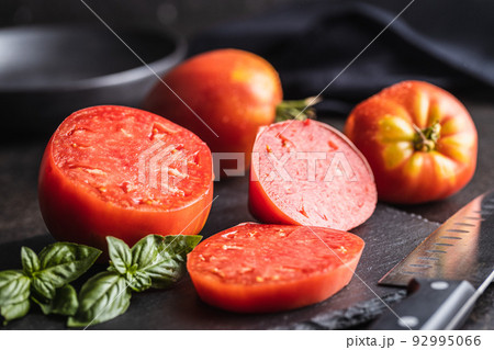 Sliced bull heart tomatoes on black table. 92995066