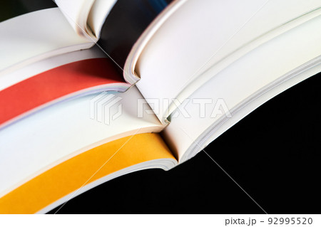 A part of a stack of open magazines on dark background 92995520