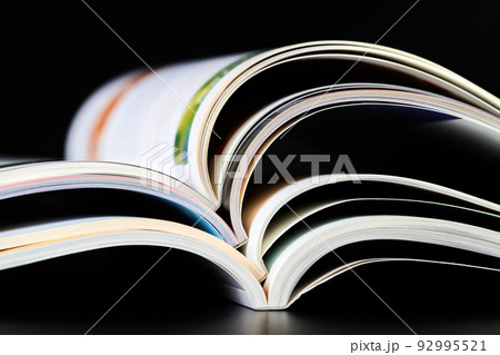 A part of a stack of open magazines on dark background A part of a stack of open magazines on dark background 92995521