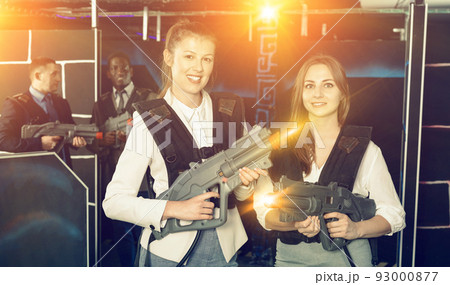 Portrait of two women in business suits playing laser tag with c Portrait of two women in business suits playing laser tag with c 93000877