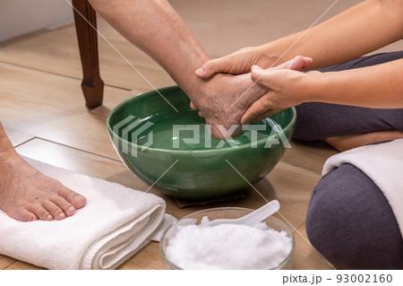 Female caregiver wipes the elderly woman feet by towel. Female caregiver wipes the elderly woman feet by towel. 93002160