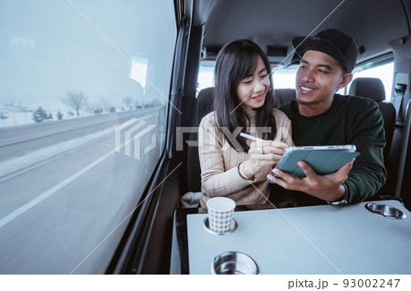 asian man and woman discussing over a tablet while on their way by car 93002247