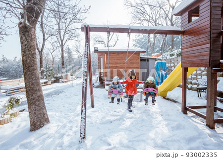 girl help swinging her brother and sister during playing 93002335