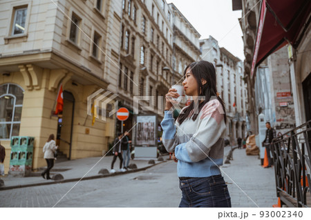 woman wearing sweater drinking her coffee while standing 93002340