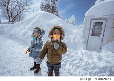 kid enjoying lollipop outside during snowy winter 93002624