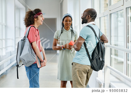 Group of teenagers talking to each other during break standing at corridor after lessons Group of teenagers talking to each other during break standing at corridor after lessons 93003832
